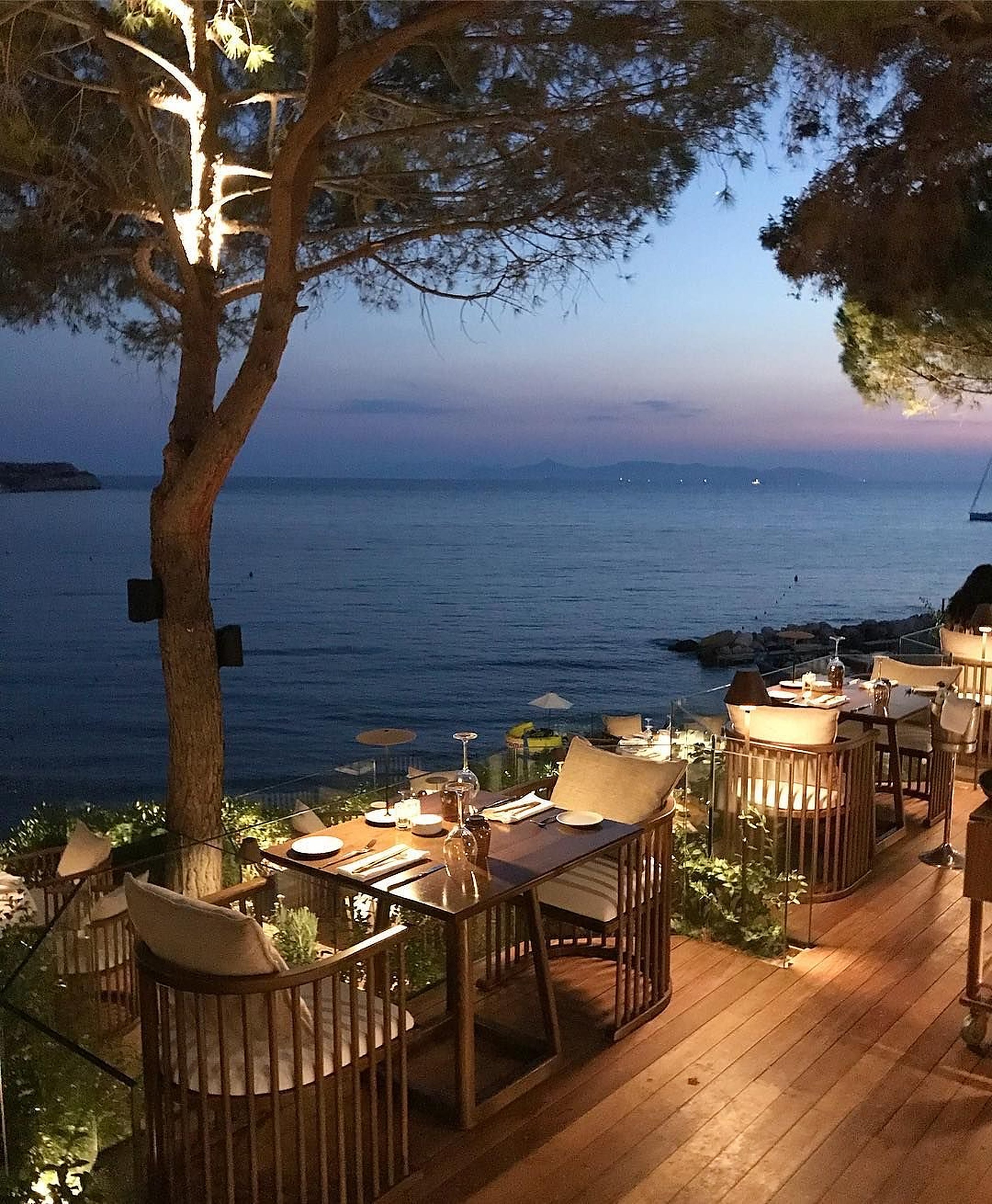 Une terrasse en bord de mer dressée pour le dîner, au crépuscule